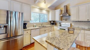 Una cocina moderna con electrodomésticos de acero inoxidable, armarios blancos y encimera de granito.