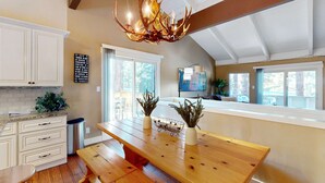 Una cocina con una mesa de madera, armarios blancos y una lámpara de araña.