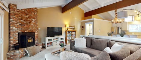 A living room with a brick fireplace, a sofa, a television, and a bookshelf.