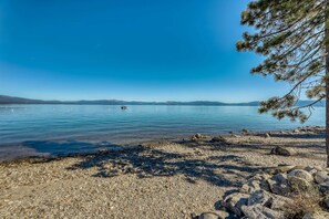 A clear lake with a rocky shoreline and a pine tree on the right. - Family-friendly home with a beautiful yard & deck - close to the lake & ski slopes (Homewood)