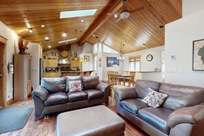 A spacious living area with leather sofas, wooden ceiling beams, and a kitchen in the background. - Immaculate Dog-Friendly Home with Private Hot Tub, Billiards, 2 Jacuzzi Tubs (South Lake Tahoe)