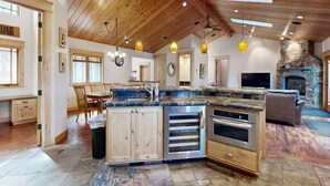 A spacious kitchen with a large island, wooden ceiling, and stone fireplace. - Immaculate Dog-Friendly Home with Private Hot Tub, Billiards, 2 Jacuzzi Tubs (South Lake Tahoe)