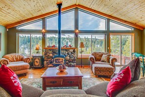A cozy living room with a stone fireplace, large windows, and wooden ceiling beams. - Elegant Mountain Retreat, Shared Hot Tub, Pool, & Resort Amenities - Near Beach (Truckee)