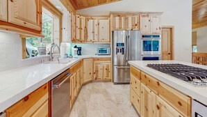 Eine moderne Küche mit Holzschränken, Edelstahlgeräten und einer weißen Arbeitsplatte.
