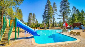 A swimming pool with a blue slide, surrounded by trees and a brick patio. - Dog-friendly snowbird escape with pool, hot tub & sauna access, & woodstove (Truckee)
