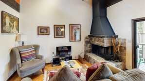 A cozy living room with a fireplace, a television, and a comfortable seating area. - Inviting condo with balconies, fireplace, outdoor pool, sauna, & fitness center (Kings Beach)