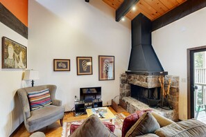 A cozy living room with a fireplace, a television, and a comfortable seating area. - Inviting condo with balconies, fireplace, outdoor pool, sauna, & fitness center (Kings Beach)