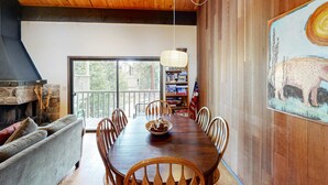A dining area with a wooden table, chairs, a fireplace, and a bookshelf. - Inviting condo with balconies, fireplace, outdoor pool, sauna, & fitness center (Kings Beach)