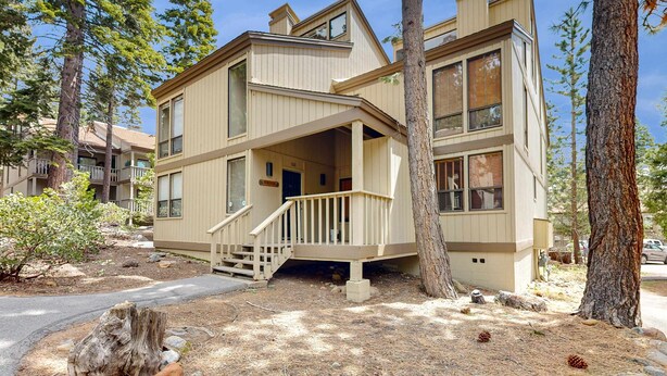 A multi-story building with a balcony, surrounded by trees. - Inviting condo with balconies, fireplace, outdoor pool, sauna, & fitness center (Kings Beach)