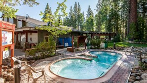 A pool area with a spa capacity sign, a covered seating area, and a building with a blue door. - Northstar condo close to skiing with pool, hot tub, gym, game room & W&D (Truckee)