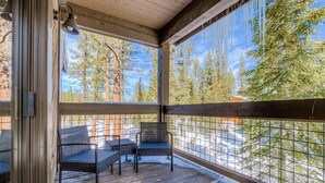 A wooden deck with chairs and a table, overlooking a snowy landscape with trees. - Northstar condo close to skiing with pool, hot tub, gym, game room & W&D (Truckee)