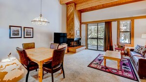 A spacious living room with a wooden ceiling, a fireplace, a television, and a large window. - Northstar condo close to skiing with pool, hot tub, gym, game room & W&D (Truckee)