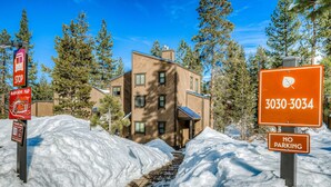 A building with a brown exterior, surrounded by snow and trees. - Northstar condo close to skiing with pool, hot tub, gym, game room & W&D (Truckee)