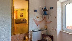 A room with a radiator, a wooden floor, a sofa, and a window. - Cozy accommodation in quiet surroundings with sea view and barbecue (Dramalj)
