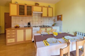 Una cocina compacta con armarios de madera, una estufa a gas y un comedor para dos personas con una mesa lista para comer.