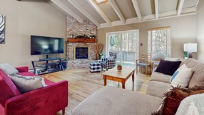 Ein großzügiges Wohnzimmer mit Fernseher, Sofas, einem Couchtisch und einem Kamin.