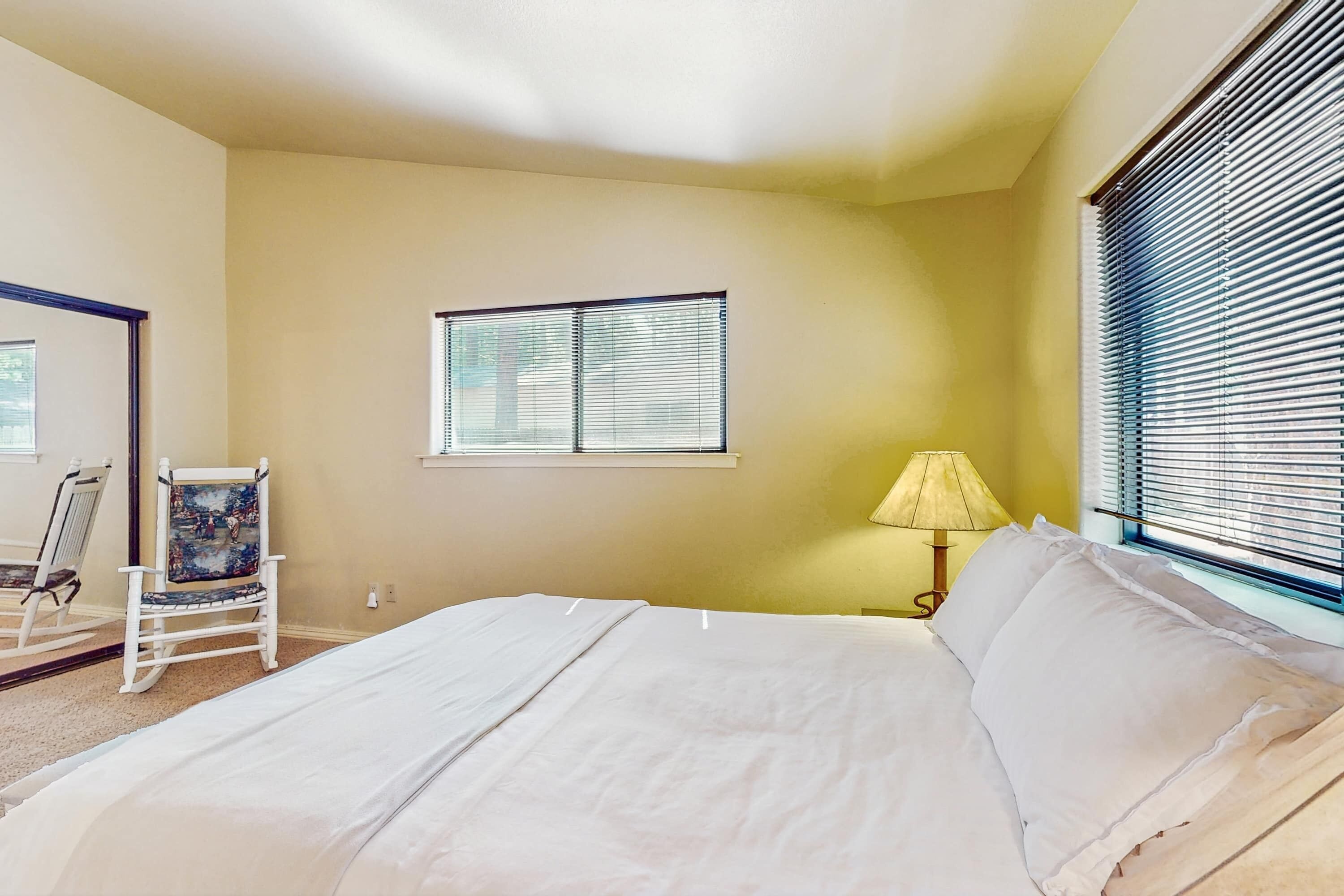 Une chambre à coucher avec un lit, une chaise, une fenêtre et une lampe.