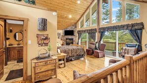 A spacious room with a fireplace, wooden furniture, a large window, and a balcony. - Large Luxury Estate Home on Golf Course with Private Indoor Heated Pool, Spa, Sauna (South Lake Tahoe)