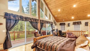 A spacious bedroom with a large bed, wooden ceiling, and a balcony with a wooden railing. - Large Luxury Estate Home on Golf Course with Private Indoor Heated Pool, Spa, Sauna (South Lake Tahoe)