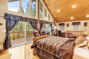 A bedroom with a large bed, wooden ceiling, and a view of a deck. - Large Luxury Estate Home on Golf Course with Private Indoor Heated Pool, Spa, Sauna (South Lake Tahoe)