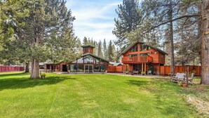 A large wooden lodge with a spacious lawn, multiple decks, and a prominent chimney. - Large Luxury Estate Home on Golf Course with Private Indoor Heated Pool, Spa, Sauna (South Lake Tahoe)
