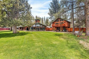 A large log cabin with a spacious deck and a covered porch, surrounded by tall trees. - Large Luxury Estate Home on Golf Course with Private Indoor Heated Pool, Spa, Sauna (South Lake Tahoe)