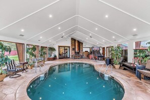 An indoor swimming pool with a clear view of the pool area, a seating area with chairs and tables, and a basketball hoop. - Large Luxury Estate Home on Golf Course with Private Indoor Heated Pool, Spa, Sauna (South Lake Tahoe)