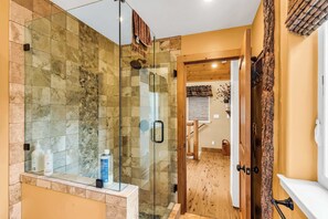 A modern bathroom with a glass-enclosed shower, a wooden door, and a visible bathroom counter. - Large Luxury Estate Home on Golf Course with Private Indoor Heated Pool, Spa, Sauna (South Lake Tahoe)