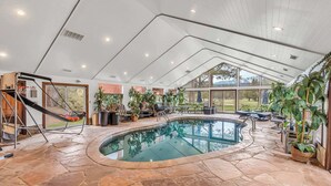 An indoor pool area with stone flooring, a slide, and potted plants. - Large Luxury Estate Home on Golf Course with Private Indoor Heated Pool, Spa, Sauna (South Lake Tahoe)
