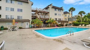 Uma área de piscina com uma piscina azul límpida, espreguiçadeiras e um deck de madeira.