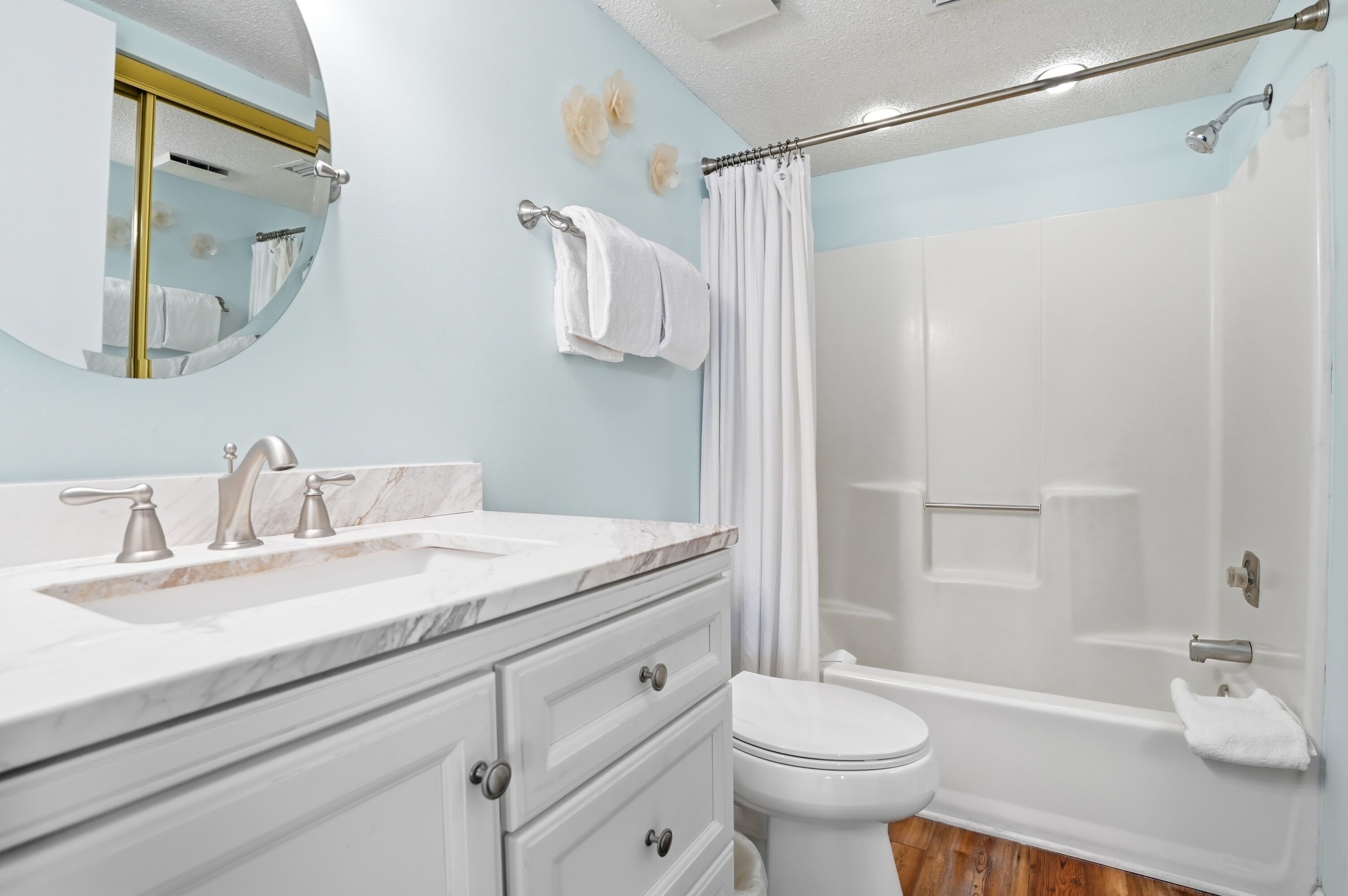 Une salle de bain avec un lavabo en marbre, des toilettes et une douche avec un rideau.
