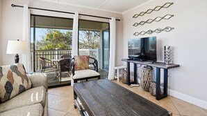 Uma sala de estar com sofá, mesa de centro, televisão e objetos decorativos.