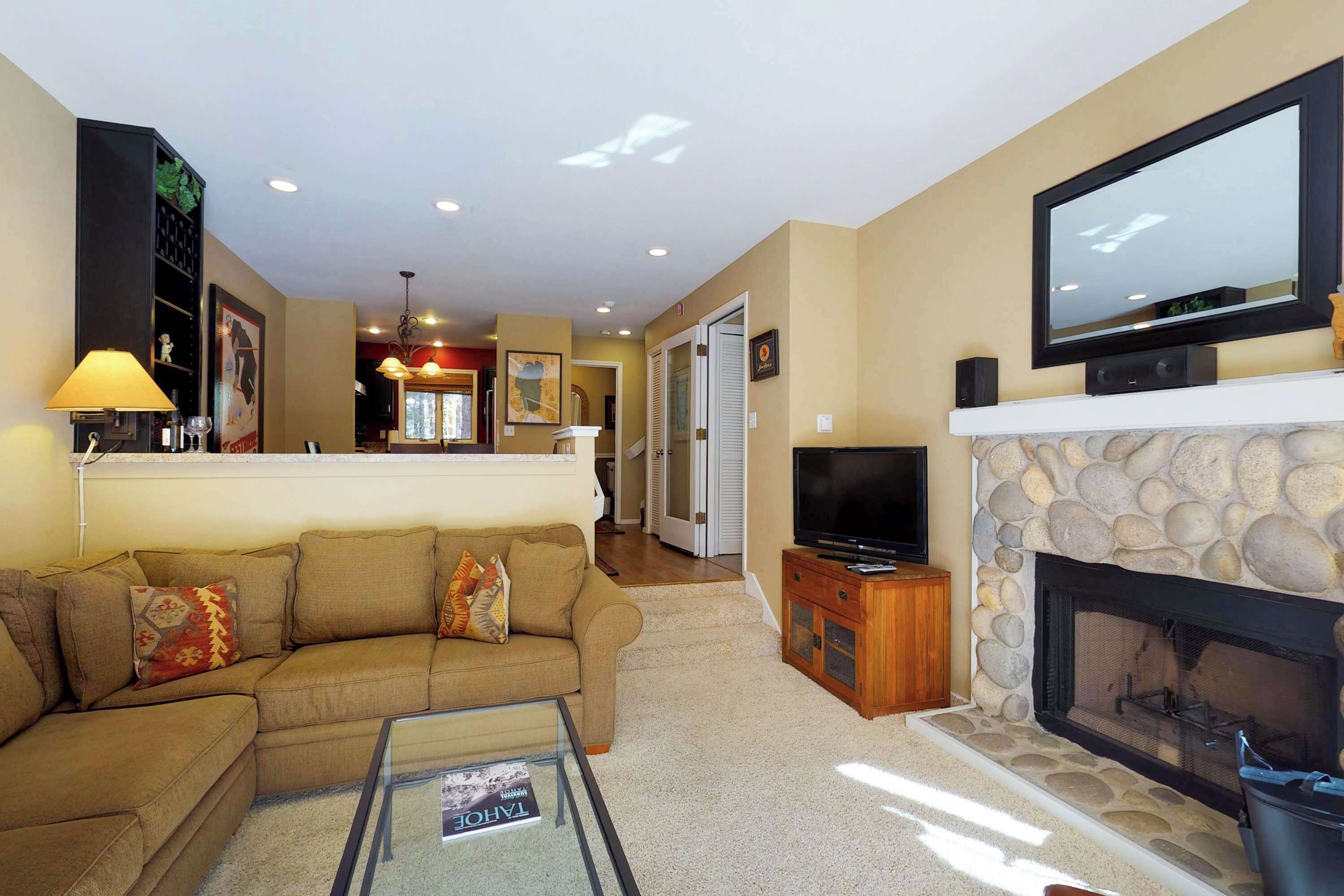 A living room with a sofa, television, fireplace, and a glass coffee table.