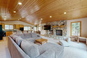 A spacious living room with a large sectional sofa, a fireplace, and a stone accent wall. - Spacious home with fireplace and two decks with hot tub & bbq grill (Tahoe Vista)