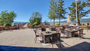 An outdoor patio with seating, a fire pit, and a view of a lake. - Lakefront retreat with shared pool, hot tub, & sauna - near shopping & skiing (South Lake Tahoe)