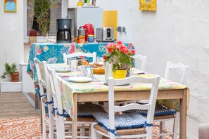 A dining area with a table set for two, chairs, a coffee machine, a toaster, and a potted plant. - Sea, Countryside in the City Center – Rooms 1+2 (Douarnenez)