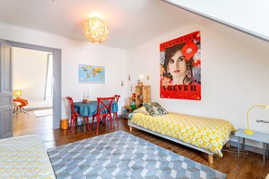 Een slaapkamer met een bed, een bureau, een stoel, een wereldbol en een poster aan de muur.