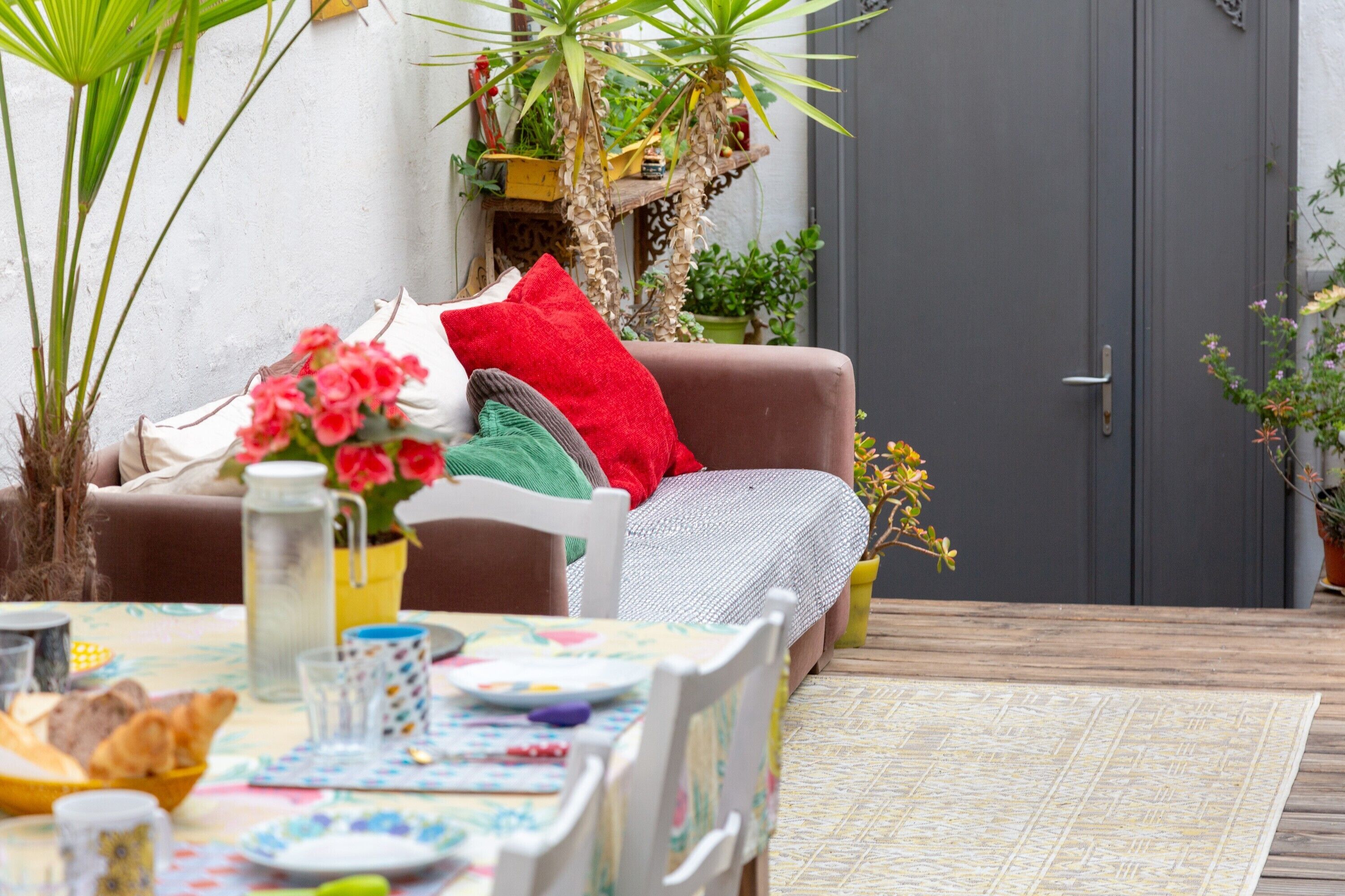 A cozy outdoor seating area with a table, chairs, and a variety of potted plants.