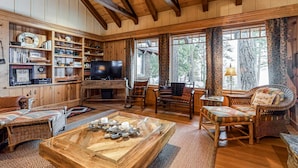 Un intérieur en bois avec une télévision, des meubles en osier et une cheminée.