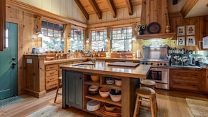 Une cuisine en bois dotée d’un grand îlot central, de meubles de rangement en bois et d’une cuisinière.