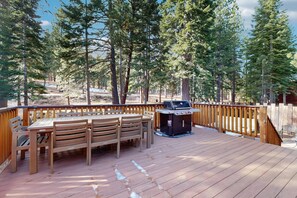 A deck with a table and chairs, surrounded by a wooden fence, and a barbecue grill. - Magical mountain home with movie theater, 9-person hot tub & full kitchen (Truckee)