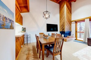Ein Essbereich mit Holztisch, einem Fernseher, einem Kamin und einem Gemälde an der Wand.