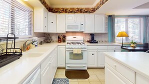 Una cocina con armarios blancos, un microondas, una estufa y un fregadero.