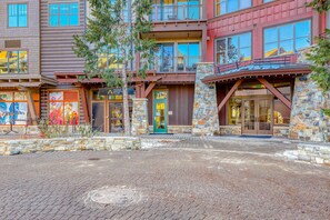 A multi-story building with a stone facade, a balcony, and a sign for a restaurant. - Modern condo with shared hot tub, fireplace, and walk to lifts - golf nearby (Truckee)