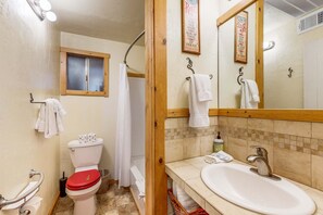 A bathroom with a toilet, shower curtain, sink, and towels.