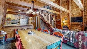 Un intérieur en bois comprenant une table à manger, des chaises, un canapé, un escalier et un coin cuisine.