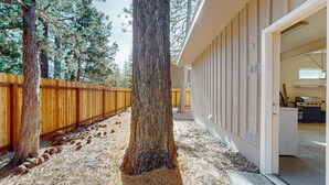 Un bâtiment à l’extérieur en bois, avec un pin devant et une porte donnant sur un espace intérieur.