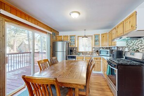 A kitchen with wooden cabinets, a dining table, and a large window.