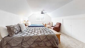 Une chambre à coucher avec un lit, un ventilateur de plafond, une fenêtre et une porte.