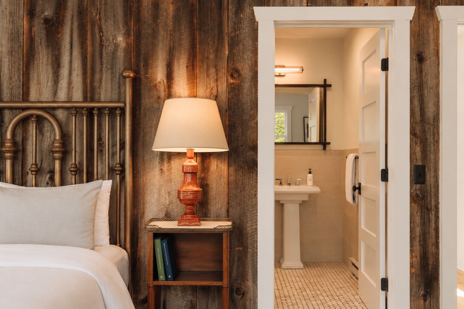A bedroom with a wooden headboard, a bedside table with a lamp, and a bookshelf.